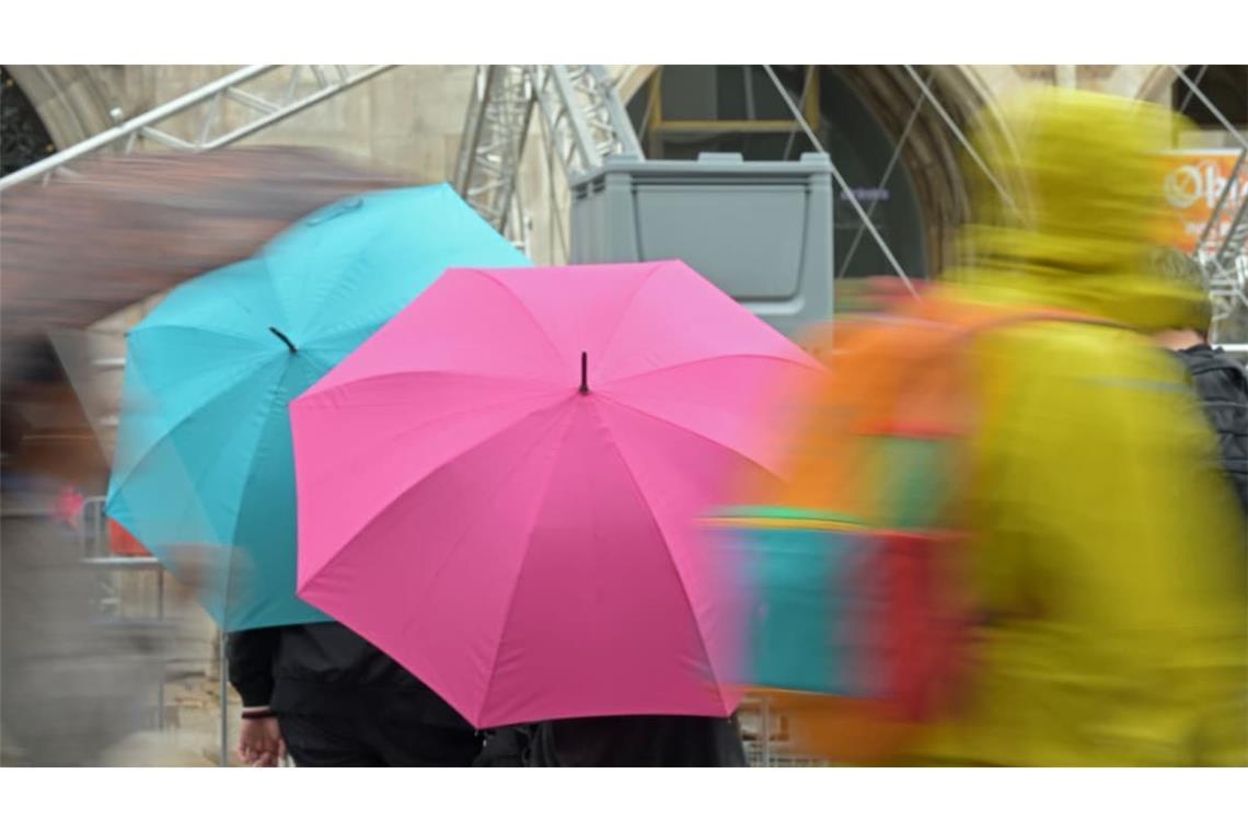 Passanten gehen mit Regenschirmen durch die Altstadt.