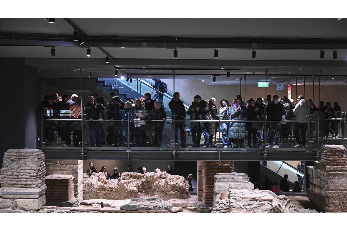 Nach 48 Jahren: Erste Metro-Linie von Thessaloniki eröffnet Pendler stehen um eine archäologische Ausgrabungsstätte in der Venizelou-Metrostation während des Eröffnungstages der Thessaloniki-Metro in Thessaloniki.