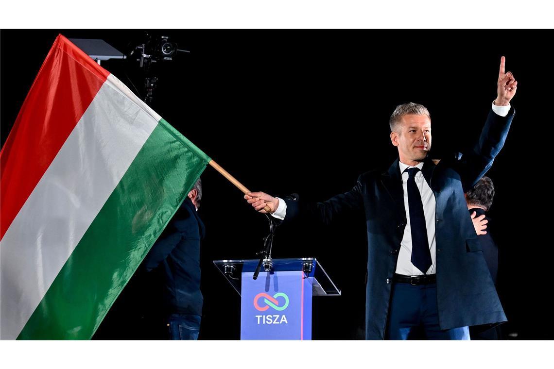 Peter Magyar, Vorsitzender der Oppositionspartei Tisza, schwenkt die ungarische Flagge nach der Bekanntgabe der Teilergebnisse der Parlamentswahl.