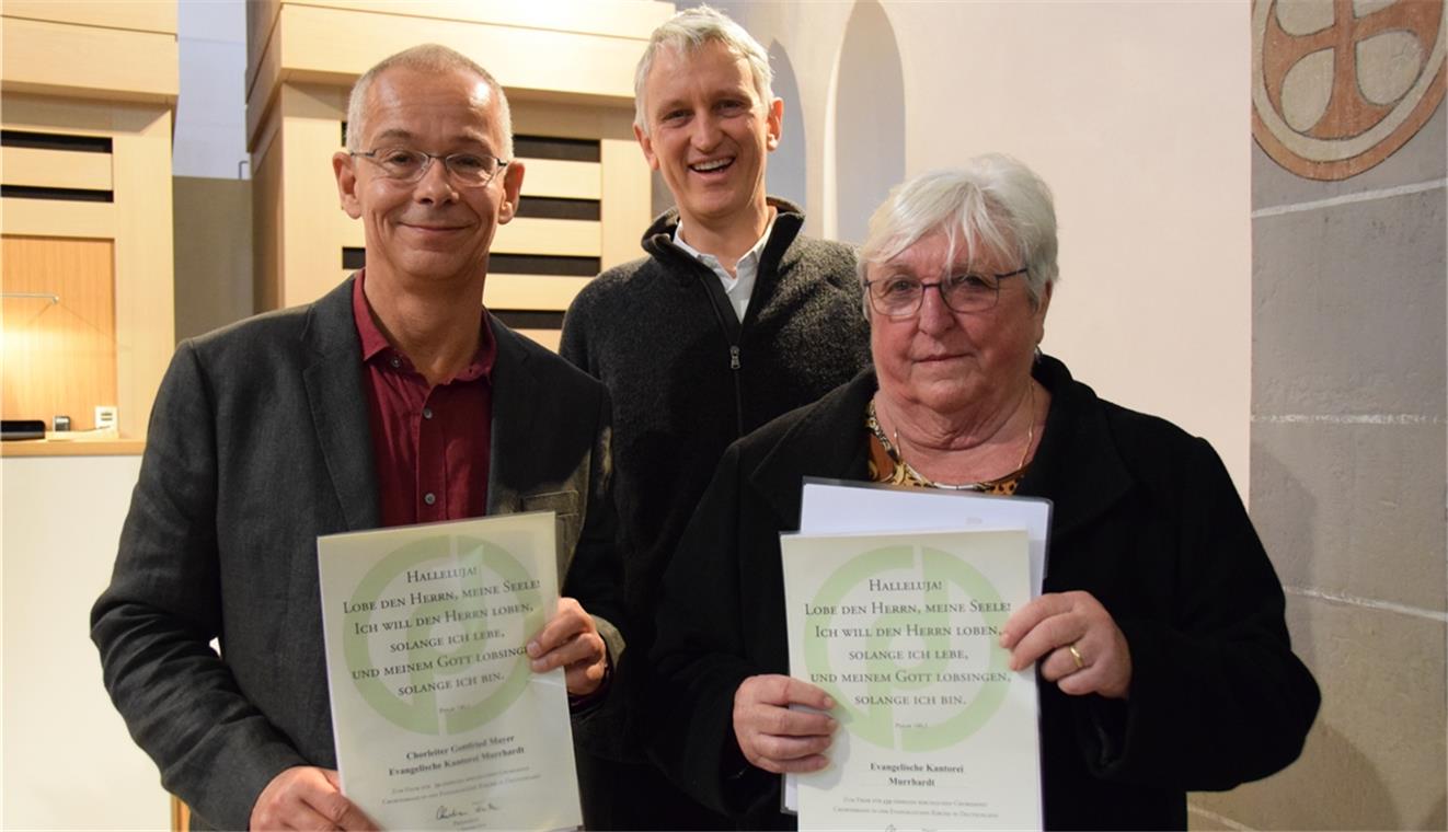 Pfarrer Hans Joachim Stein (Mitte) nutzt das Jubiläum für zwei Ehrungen: Heide Schneider (rechts) ist seit über 60 Jahren in der Kantorei und Gottfried Mayer leitet sie seit einem Vierteljahrhundert.