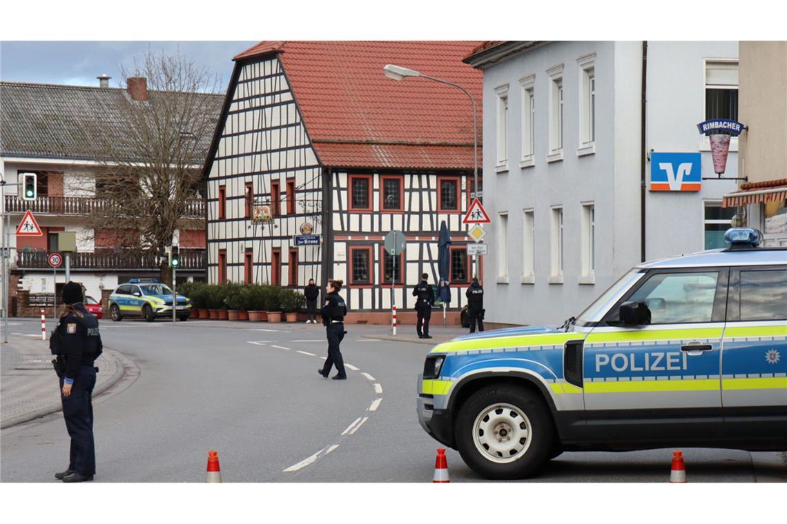 Täter hält Bankmitarbeiterin stundenlang fest - Motiv unklar Polizeibeamte sichern die Straße rund um die Bankfiliale.