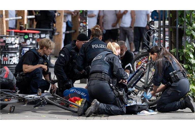Polizisten knien in der Nähe des Frankfurter Hauptbahnhofs am Boden und kümmern sich um einen Verletzten.