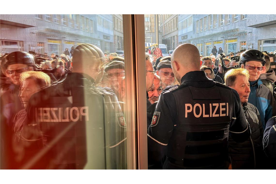 Polizisten sichern den Eingang der Sparkassenfiliale in Gelsenkirchen, vor der viele besorgte Kunde stehen und Informationen nach dem Einbruch in den Tresorraum verlangen.