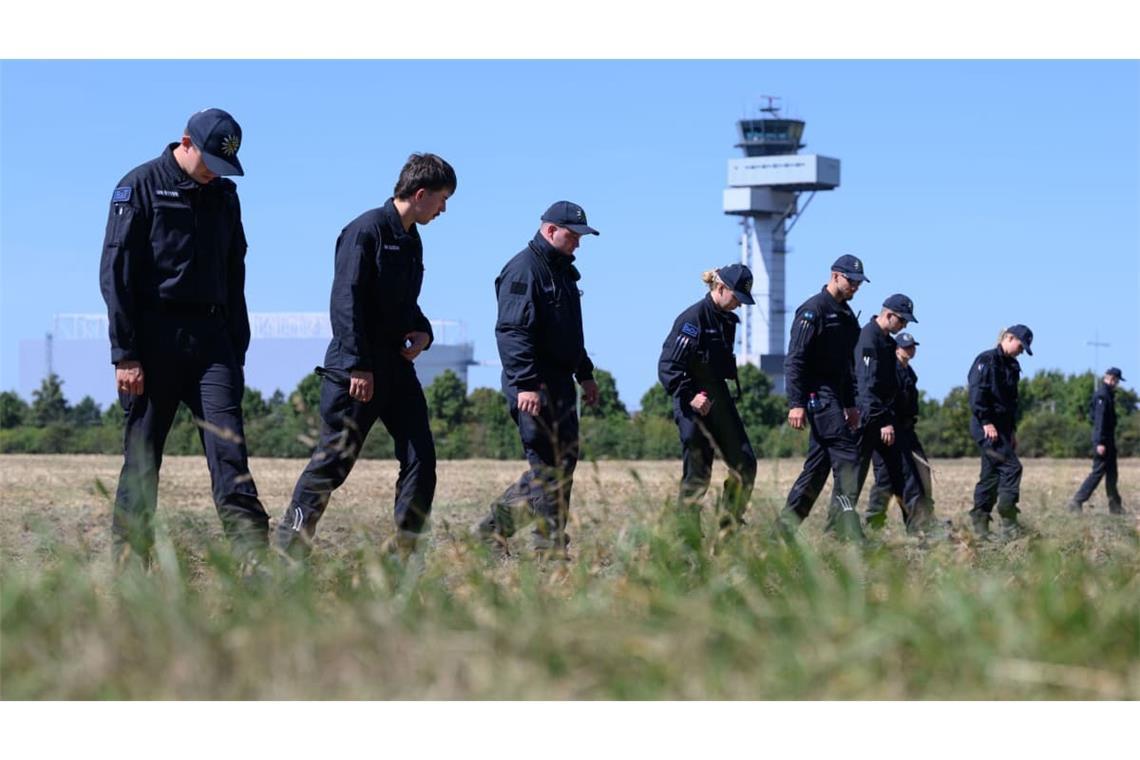 Polizisten suchen nach dem Vorfall am Flughafen Leipzig/Halle die Umgebung ab. Auf einem angrenzenden Feld wurden sie offenbar fündig.