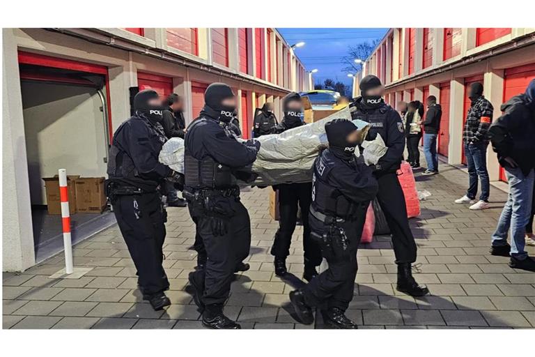 Polizisten tragen aus Lagerräumen minderwertige Schlauchboote, mit denen Menschen nach England gebracht werden sollten.