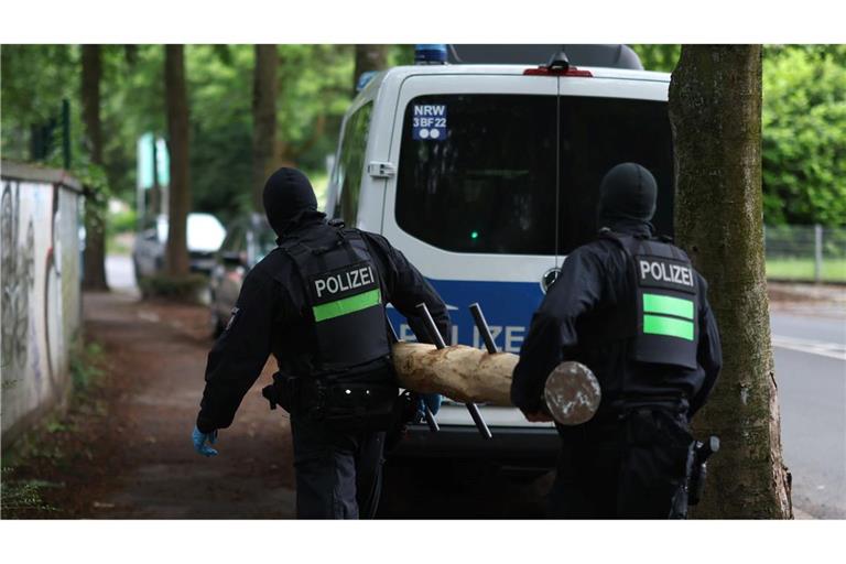 Polizisten tragen einen Rammbock.