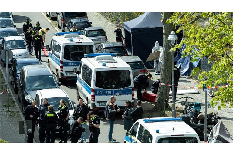 Polizisten und Beamte der Spurensicherung in weißen Schutzanzügen stehen an dem Ort, wo ein toter Mann gefunden wurde.