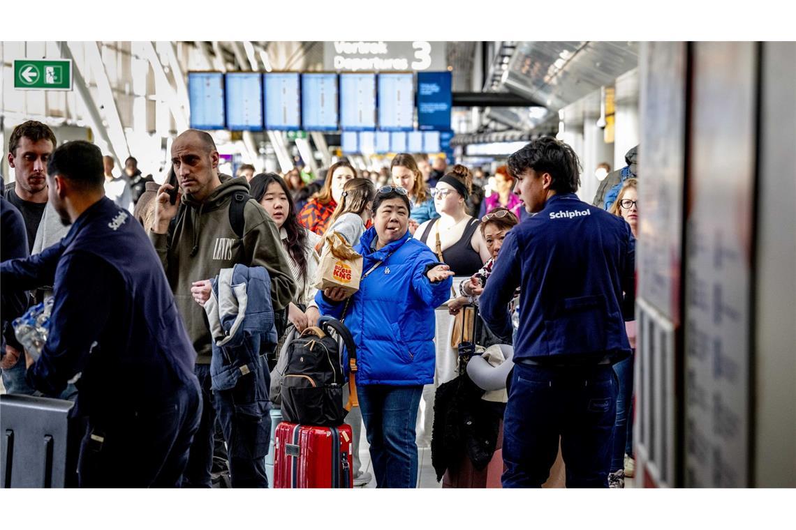 Reisende stehen Schlange am Serviceschalter der Fluggesellschaft KLM am Flughafen Schiphol.