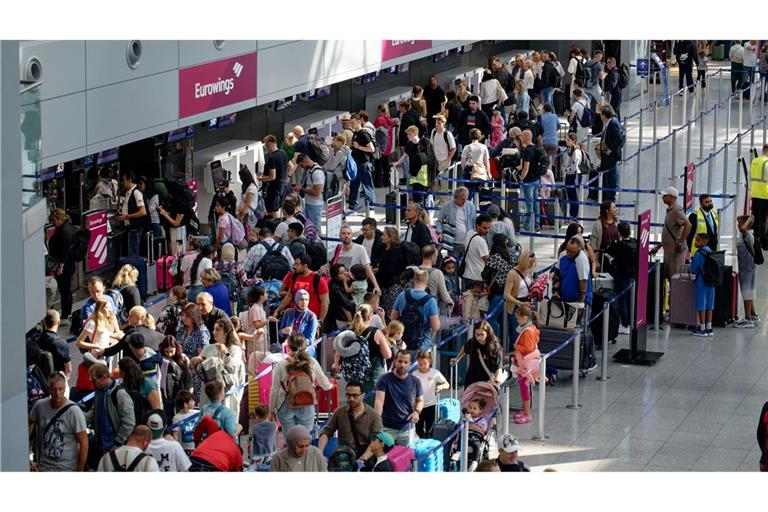 Reisende warten an Schaltern im Flughafen Düsseldorf auf die Abfertigung.