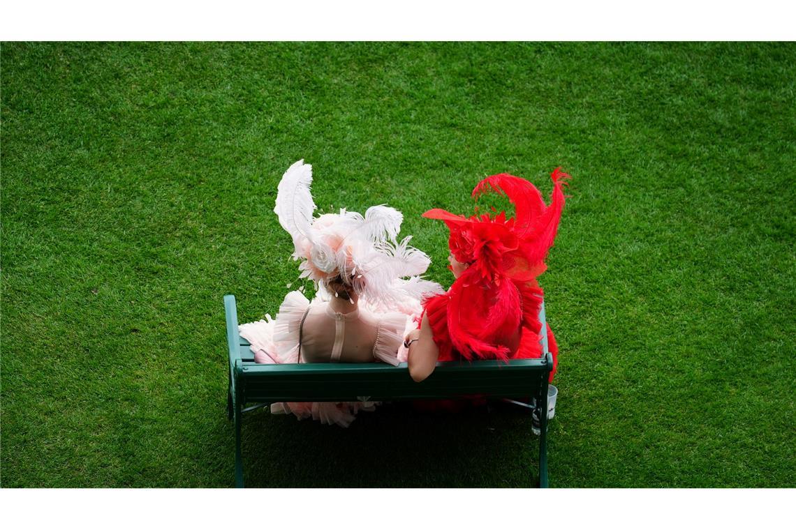 Rennbesucherinnen sitzen auf einer Bank am ersten Tag des Royal Ascot auf der Pferderennbahn von Ascot.