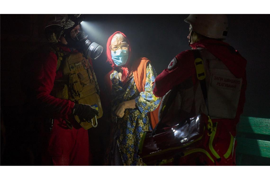 Rettungskräfte evakuieren eine ältere Bewohnerin nach dem Einschlag einer russischen Rakete in ein mehrstöckiges Wohnhaus außerhalb von Kiew.