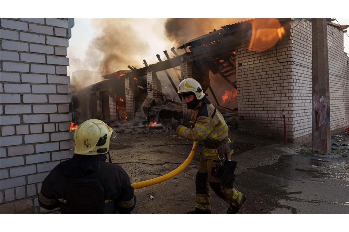 Rettungskräfte löschen ein Feuer in einer Kiewer Autowerkstatt, die durch einen russischen Angriff beschädigt wurde.