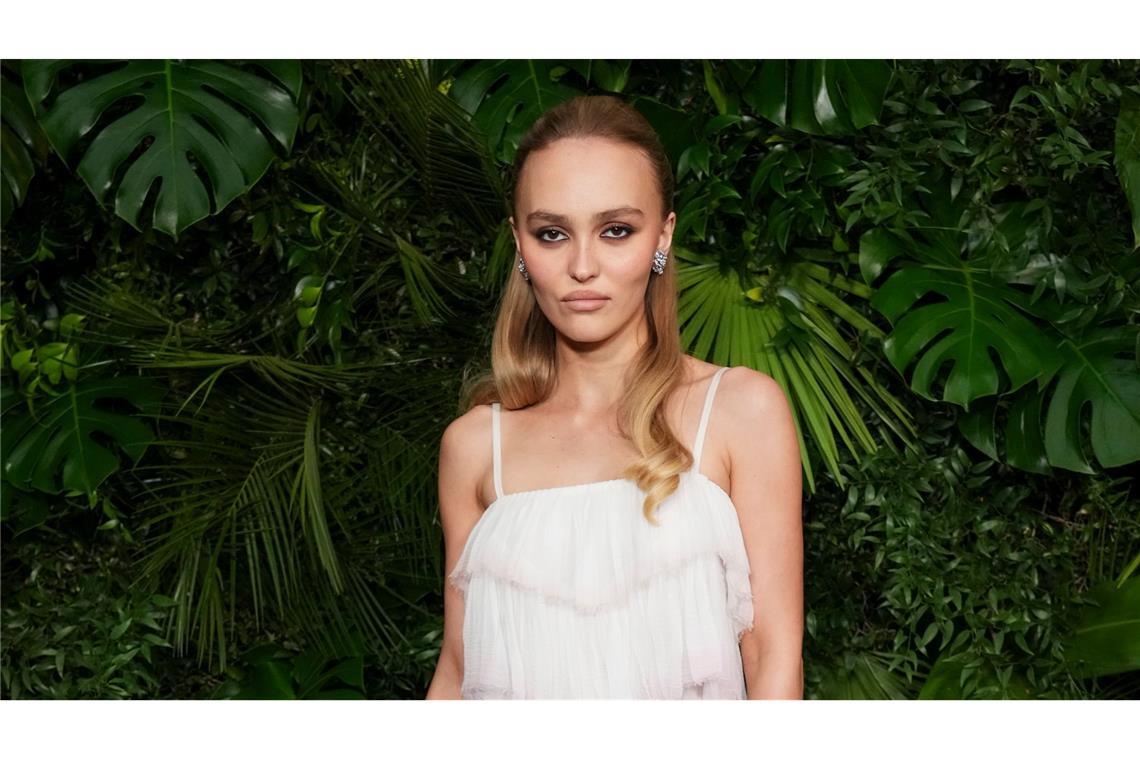Schauspielerin Lily-Rose Depp schaut in typischer roter Teppich-Pose mit kühler Miene in die Kamera. (Archivbild)