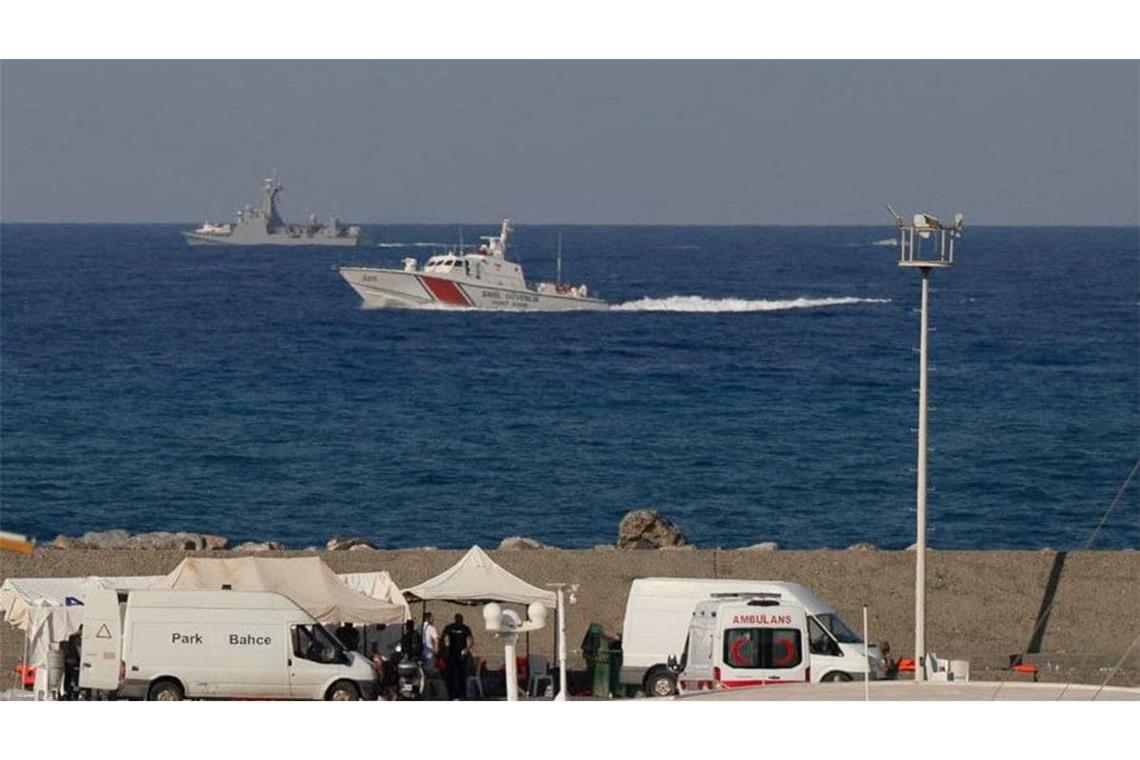 Schiffe fahren in der Nähe des Hafens von Kyrenia vorbei, während im türkisch besetzten Norden Zyperns ein Krankenwagen am Ufer geparkt ist, nachdem vor der Nordküste der Insel eine Passagierfähre gekentert war.