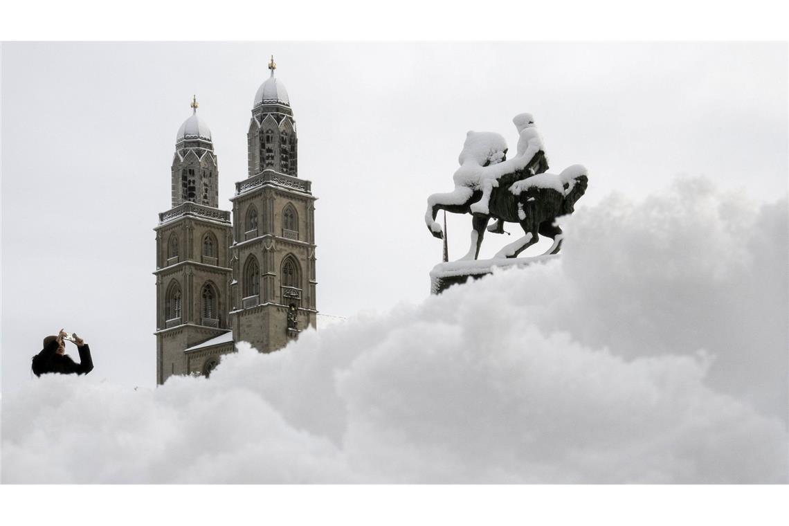 Bilder des Tages Schnee in der Schweiz: Ein Mann fotografiert das Großmünster in Zürich.