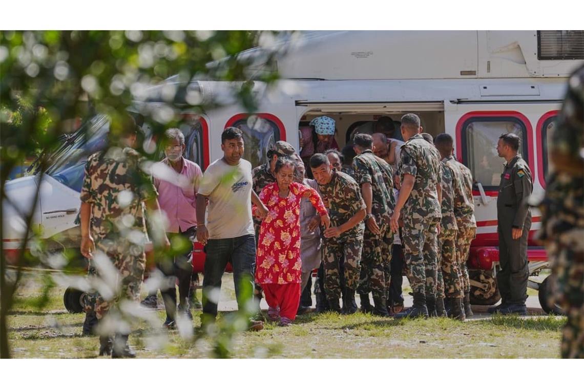 Soldaten der Armee helfen am 29. August einer Familie beim Aussteigen aus einem Hubschrauber, nachdem sie aus einem von Sturzfluten betroffenen Gebiet im nepalesischen Distrikt Nuwakot gerettet wurden.
