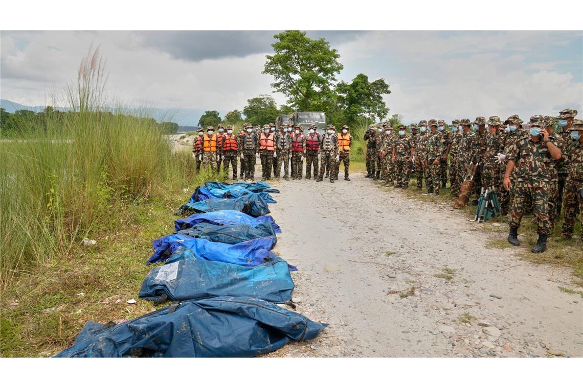 Soldaten der nepalesischen Armee warten, nachdem die Leichen von Opfern der Sturzflut aus einem Fluss geborgen haben. (zu dpa: «Überall Leichensäcke: Mehr als 1.000 Tote nach Himalaya-Flut»)