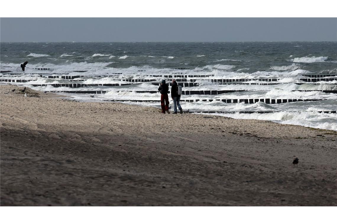 Bilder des Tages Spaziergänger sind am Ostseestrand bei Graal-Müritz unterwegs, wobei nur ab und zu etwas Sonne durch die grauen Wolken am Himmel fällt.