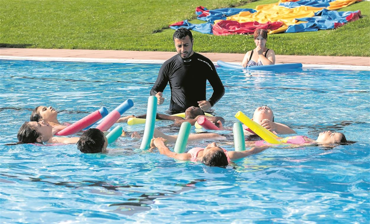 Spielerisch die Angst verlieren: Abdulfatt Wis zeigt den Kindern mit ihren Schwimmnudeln, wie die Haltung im Wasser sein sollte. Foto: J. Fiedler