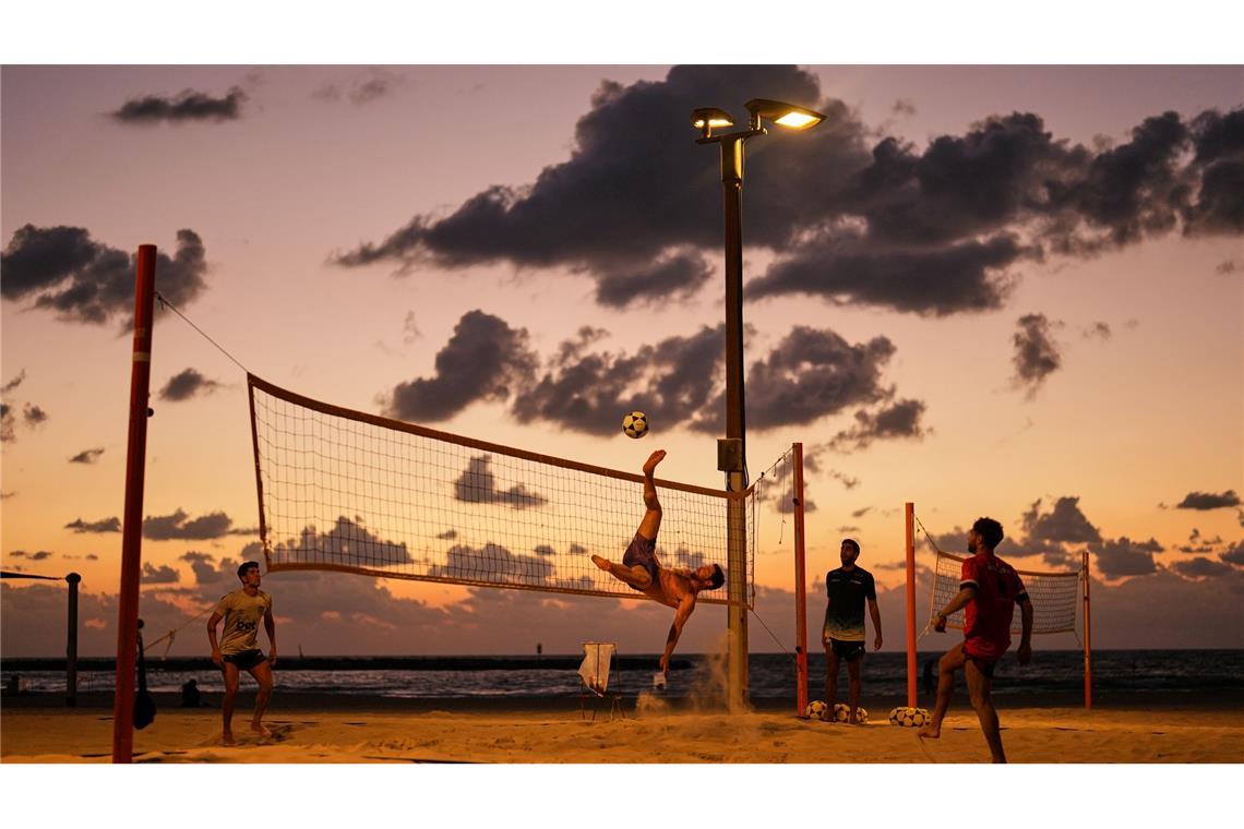 Strandbesucher spielen Fußball und Volleyball am Mittelmeer in Tel Aviv.
