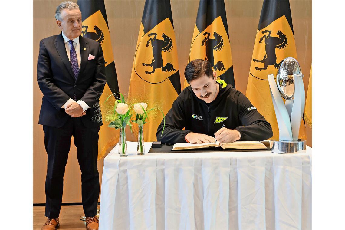 Eine große Ehre – und viele offene Fragen Surge-Teamkapitän Luis Bach trägt sich ins Goldene Buch der Stadt Stuttgart ein – unter den Augen von OB Frank Nopper.
