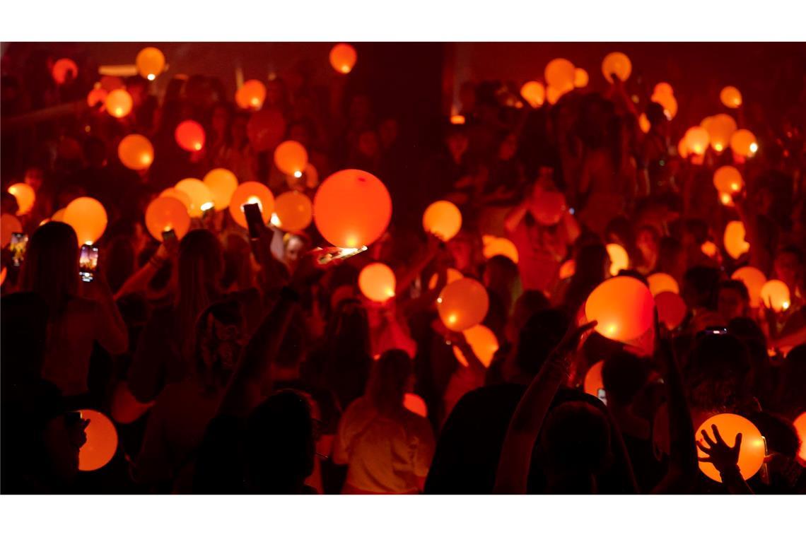 Bilder des Tages "Swifties" erleuchten in Bochum auf einer Party der Reihe "Taylor Party Europe" orangefarbene Luftballons mit den Lichtern ihrer Smartphones.