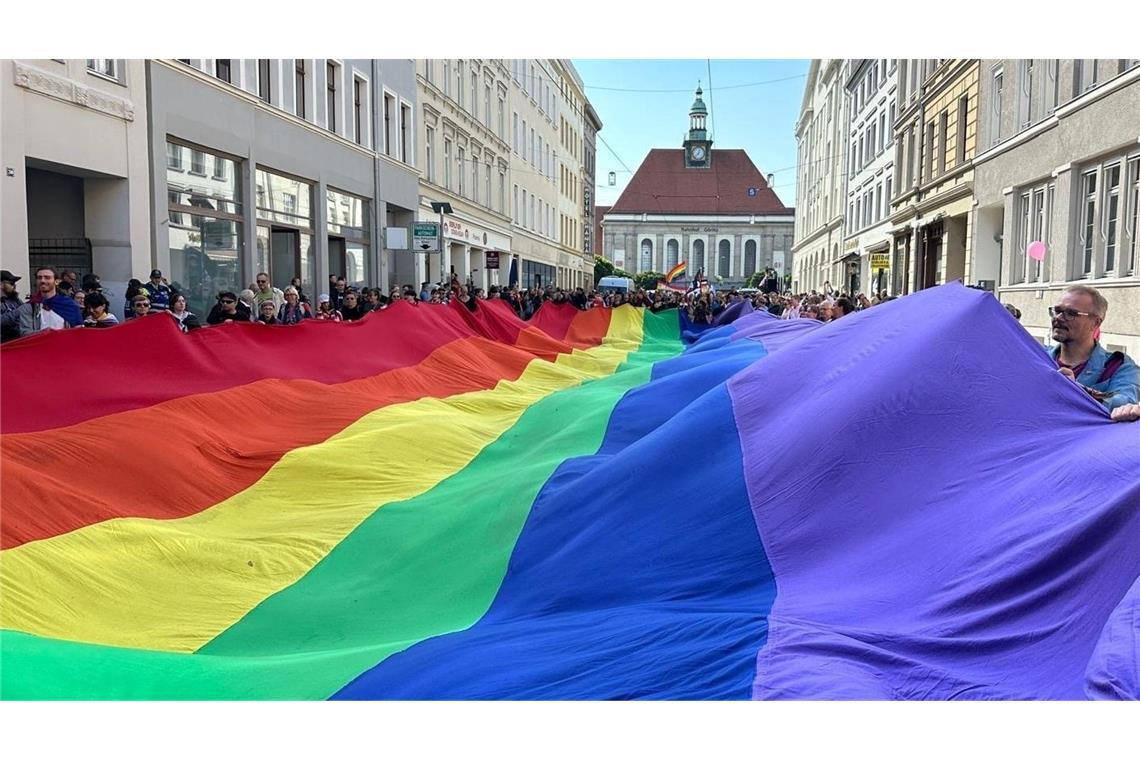 Teilnehmer ziehen mit einer überdimensionalen Regenbogenfahne beim 4. Christopher Street Day (CSD) durch die Stadt.