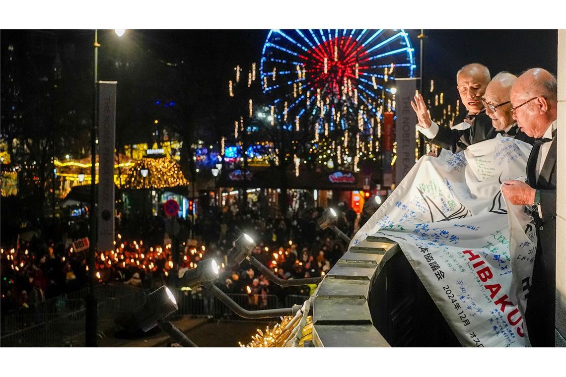Bilder des Tages Toshiyuki Mimaki, Terumi Tanaka und Shigemitsu Tanaka, Vertreter des diesjährigen Friedensnobelpreisträgers Nihon Hidankyo oder der Japan Confederation of A- and H-Bomb Sufferers Organizations, betrachten einen Fackelzug vom Balkon des Grand Hotels Oslo.