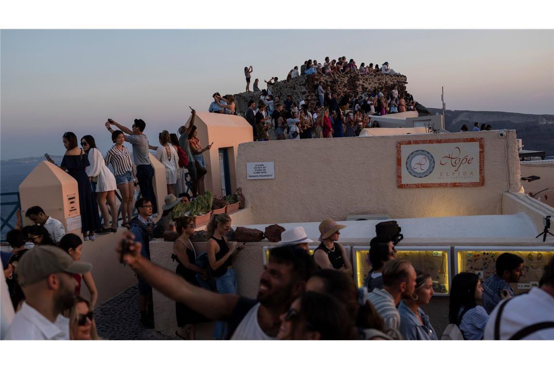 Touristen machen Selfies und genießen den Sonnenuntergang in Oia auf der Insel Santorini (Archivfoto).