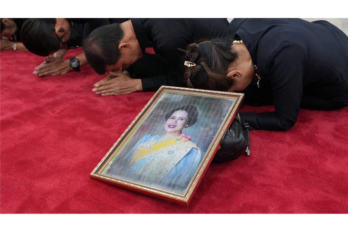 Trauernde beten in Bangkok mit einem Porträt der Königinmutter Sirikit.