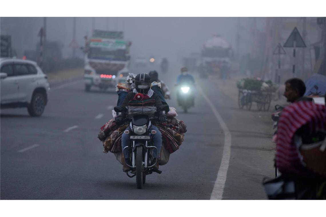 Trübe Sicht: Ein Händler transportiert seine Ware per Motorrad und fährt damit durch dichten Nebel im indischen Jammu.