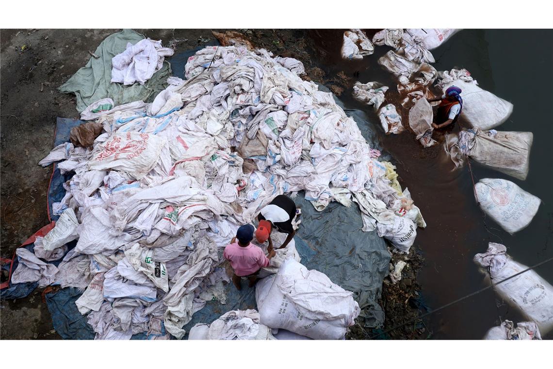 Bilder des Tages Umwelt und Existenz: Arbeiter reinigen kontaminierte Plastiksäcke im Turag-Fluss zur Wiederverwendung