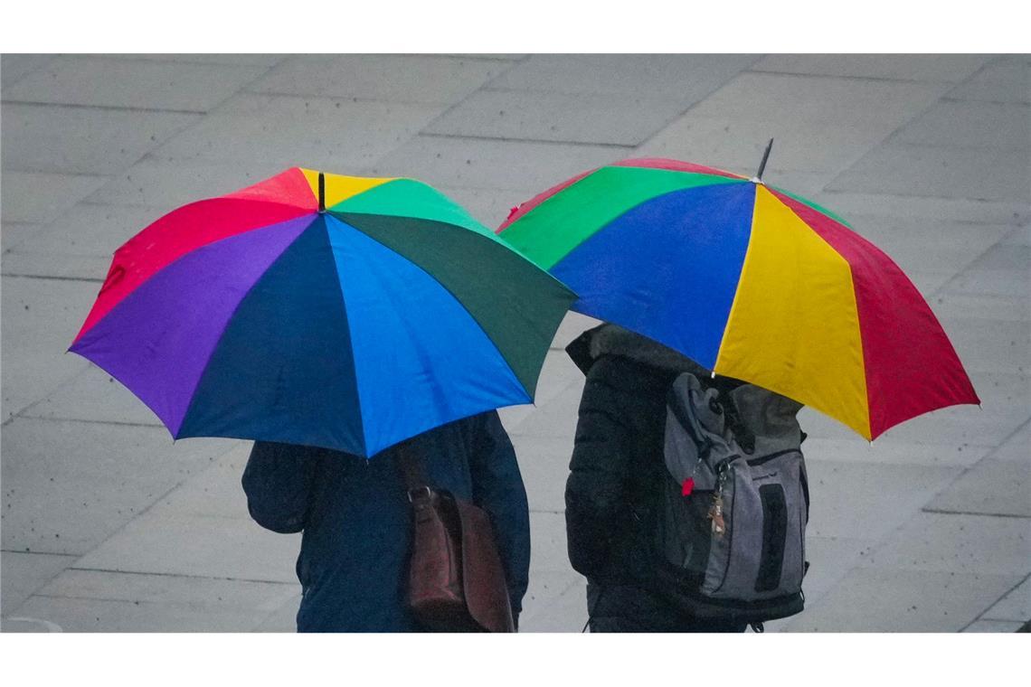 Bilder des Tages Unter bunten Regenschirmen suchen zwei Passanten Schutz vor leichtem Regen in der Potsdamer Innenstadt.