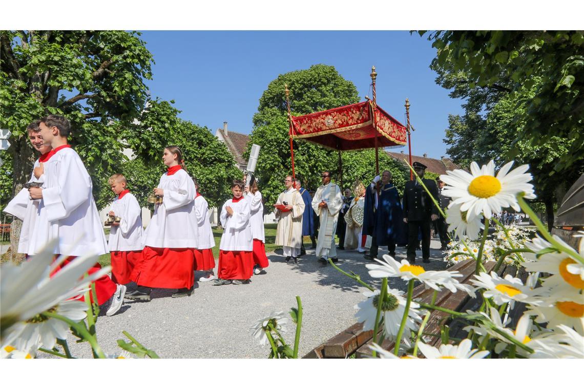 Was wird an Fronleichnam gefeiert? Unter einem Stoffbaldachin wird die Monstranz während der Fronleichnamsprozession am 8. Juni 2023 durch die Straßen des Dorfes Obermarchtal getragen.