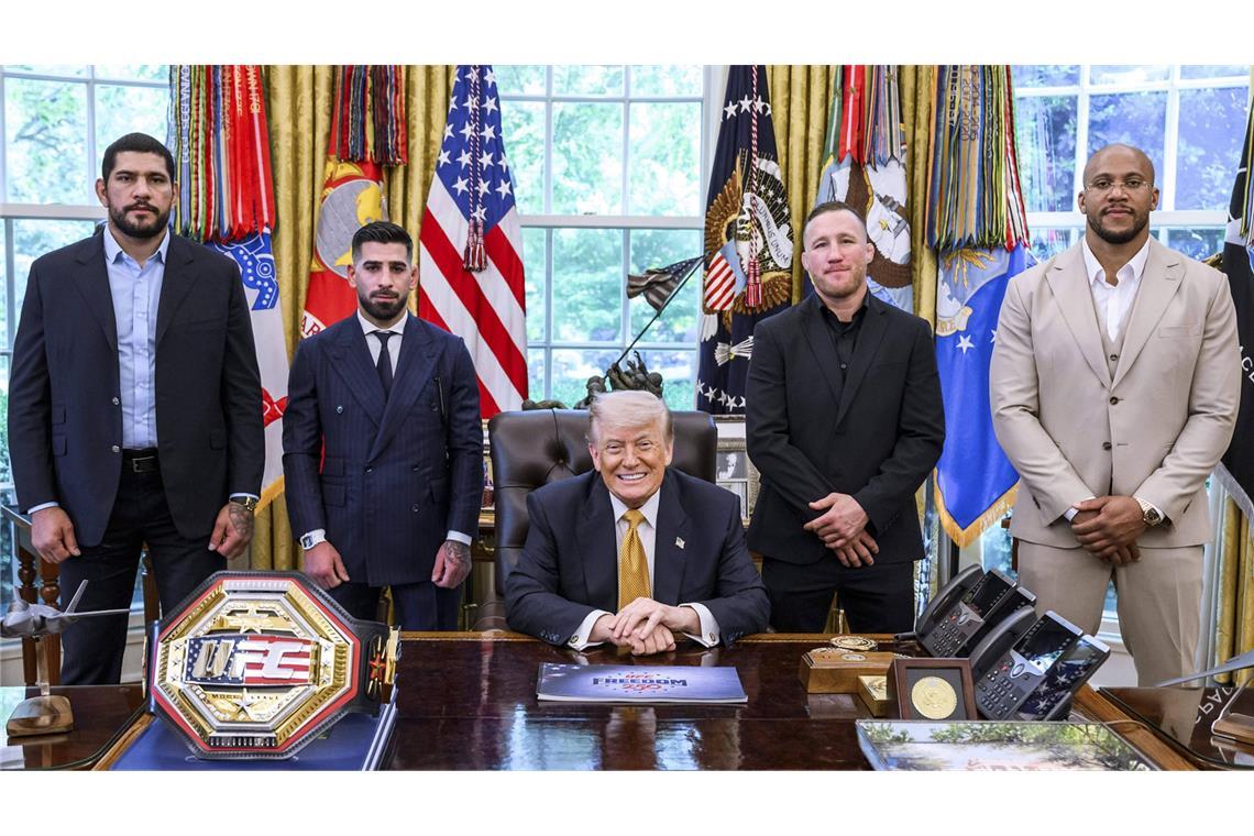 US-Präsident Donald Trump posiert am 7. Mai 2026 im Oval Office im Weißen Haus sichtlich zufrieden mit MMA-Kämpfern.