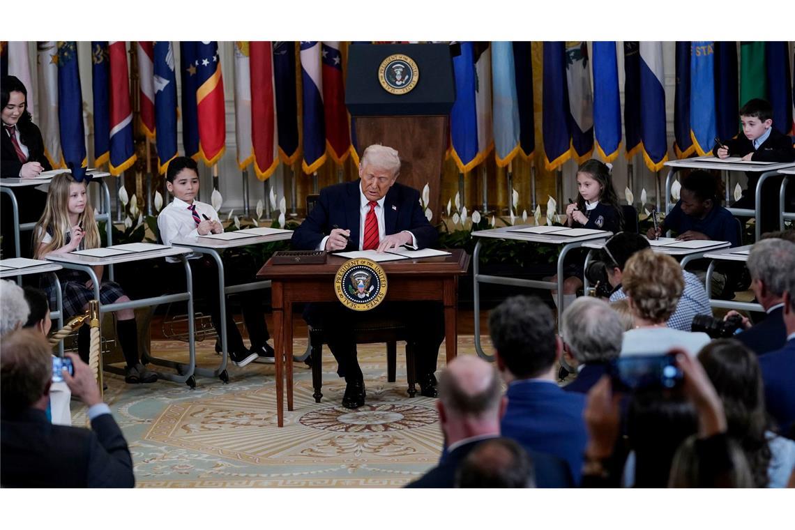 Bilder des Tages US-Präsident Donald Trump unterzeichnet umgeben von Kindern eine Anordnung im East Room des Weißen Hauses.