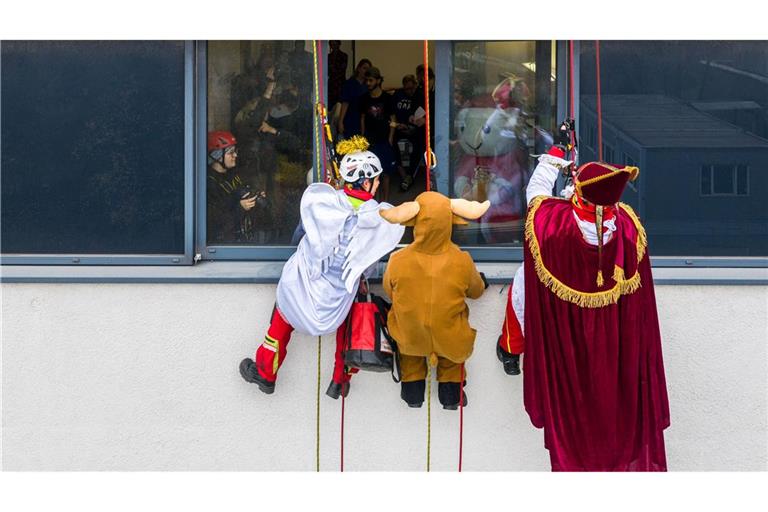 Verkleidete Höhenretter seilen sich von einem Gebäude des Herzzentrums Duisburg ab, um kleinen Patienten im Kinderherzzentrum Geschenke zu bringen.