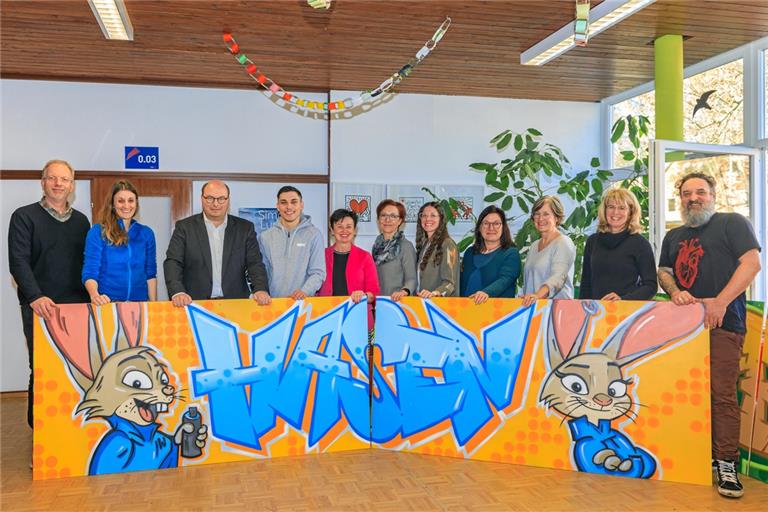 Vertreterinnen und Vertreter des Kinderbildungszentrums und seiner Partner (von links): Carsten Gehring, Rektor der Herzog-Christoph-Schule, Walterichschullehrerin Melanie Mayer, Bürgermeister Armin Mößner, Graffitikünstler Richard Koch, Iwona Kolodziejczyk von der Kernzeitenbetreuung, Silvia Mörsel, stellvertretende Leiterin des Stadthallenkindergartens, Svenja Kaufmann, Lehrerin an der Herzog-Christoph-Schule, Kibiz-Fachberaterin Rebecca Rieger, Schulsozialarbeiterin Margit Körner, Walterichschulrektorin Martina Mayer und Schulsozialarbeiter Achim Strack vor dem Hasen-Klassentierdoppelbild. Foto: Stefan Bossow