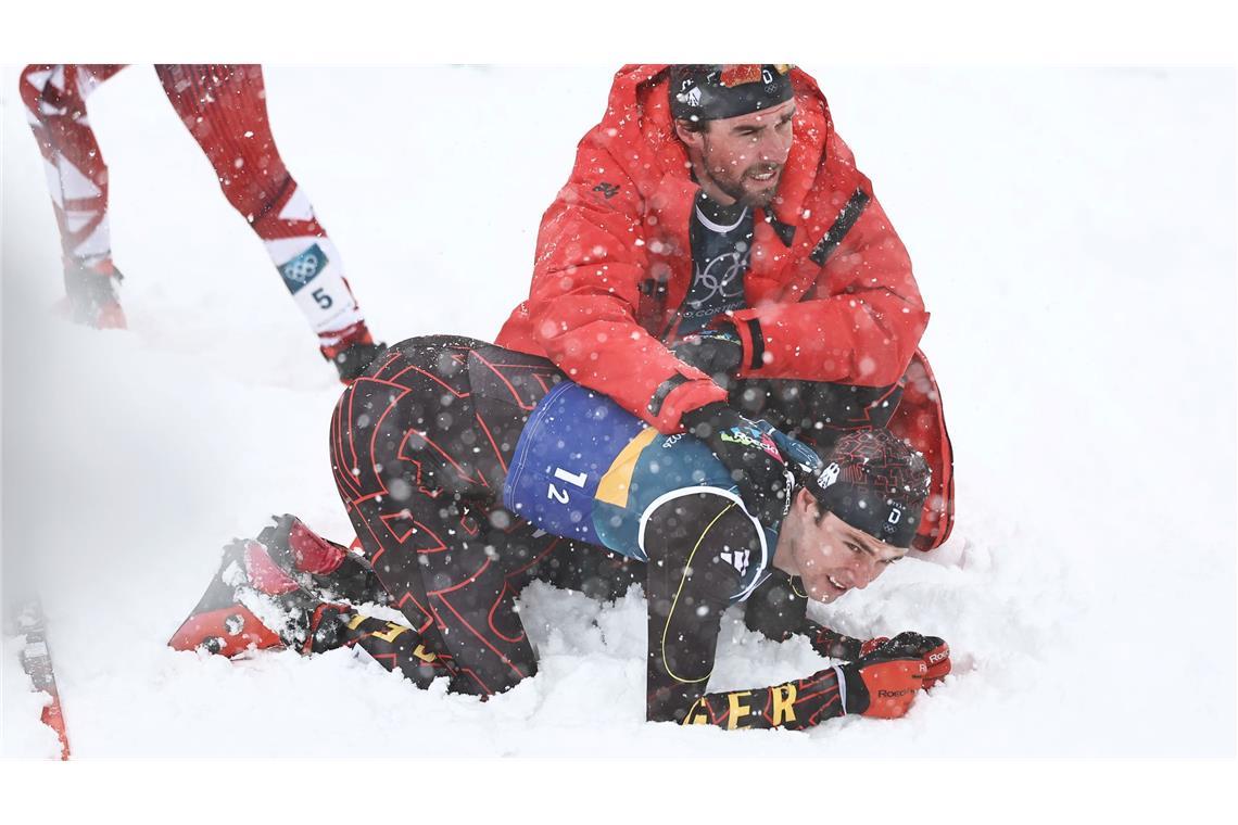 Vinzenz Geiger liegt im Schnee und wird von Teamkollege Johannes Rydzek getröstet.