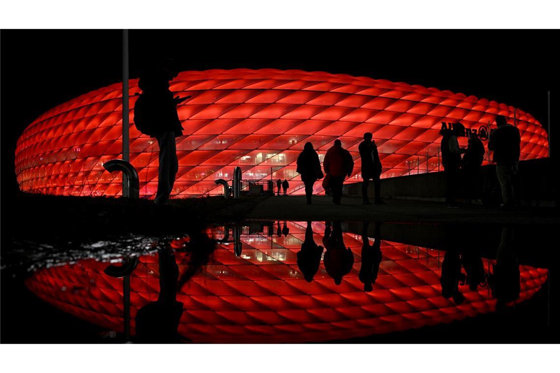 Bilder des Tages Vor dem Spiel von Bayern München gegen Paris Saint-Germain kommen Zuschauer an der Arena an, die im Dunkeln rot beleuchtet wird.