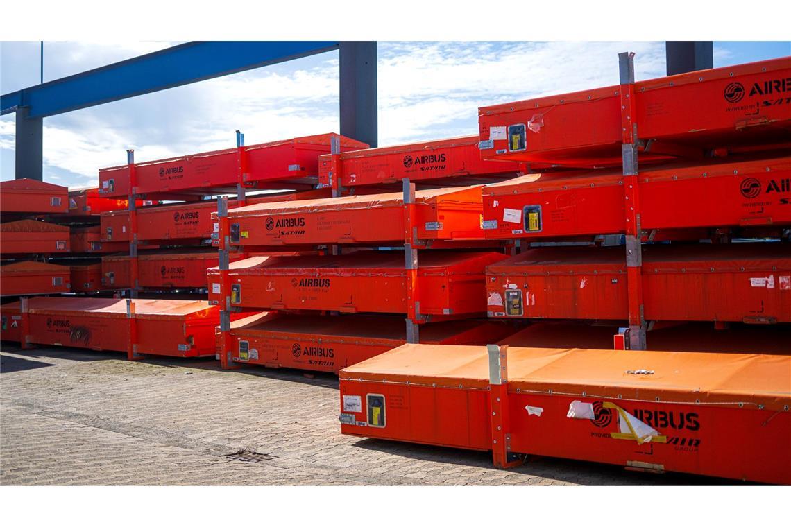 Vor der Werkhalle warten beschädigte Fahrzeugteile auf die Reparatur.