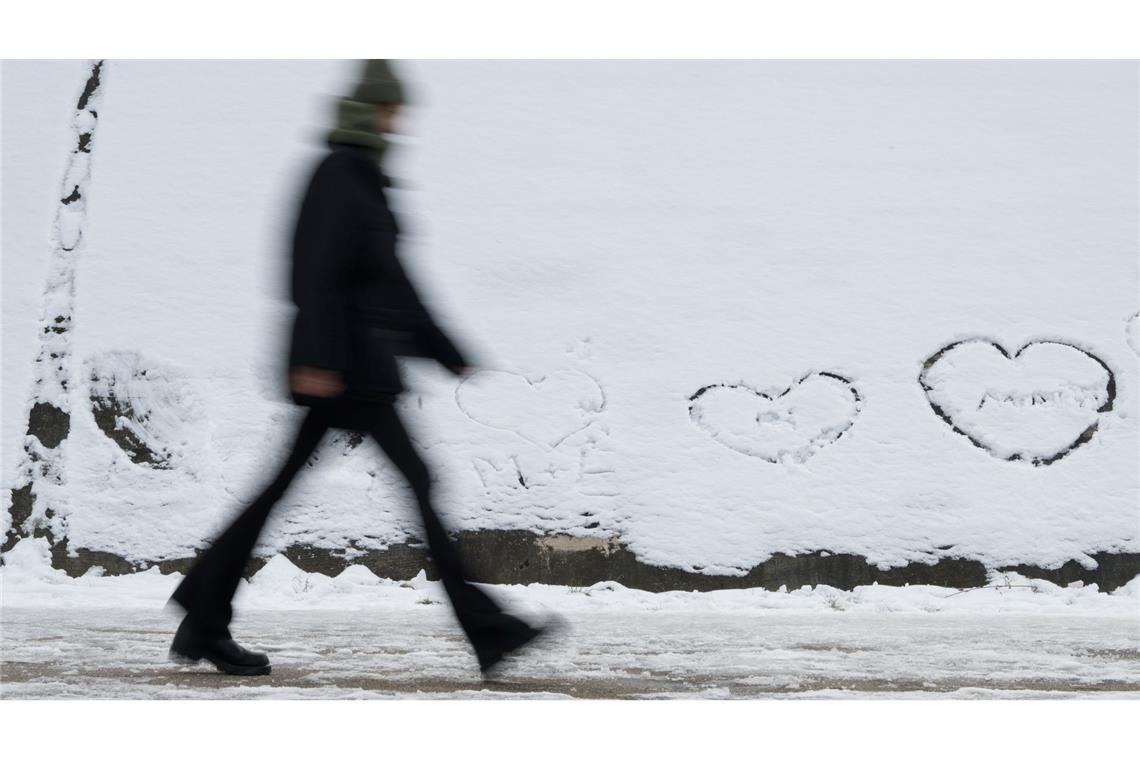 Bilder des Tages Winterwetter in Berlin: Eine Person geht an einer Wand vorbei, auf der im Schnee Herzen geschrieben sind.