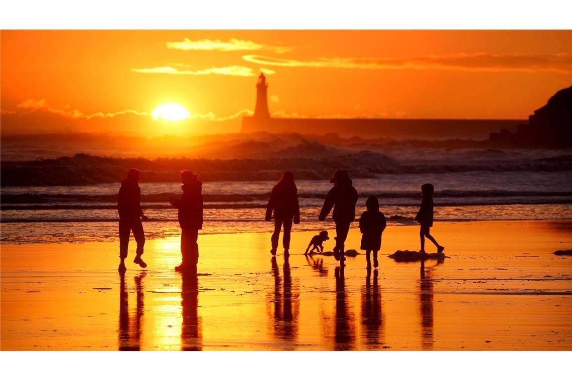 Bilder des Tages Winterwetter in Großbritannien: Spaziergänger gehen bei Sonnenaufgang am Strand von Tynemouth