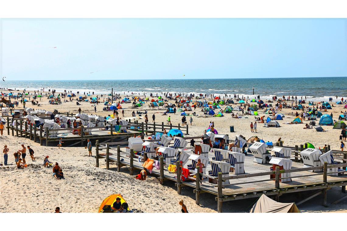 Zahlreiche Menschen sind bei strahlendem Sonnenschein am Strand von St. Peter Ording an der Nordsee unterwegs. (Archivbild)