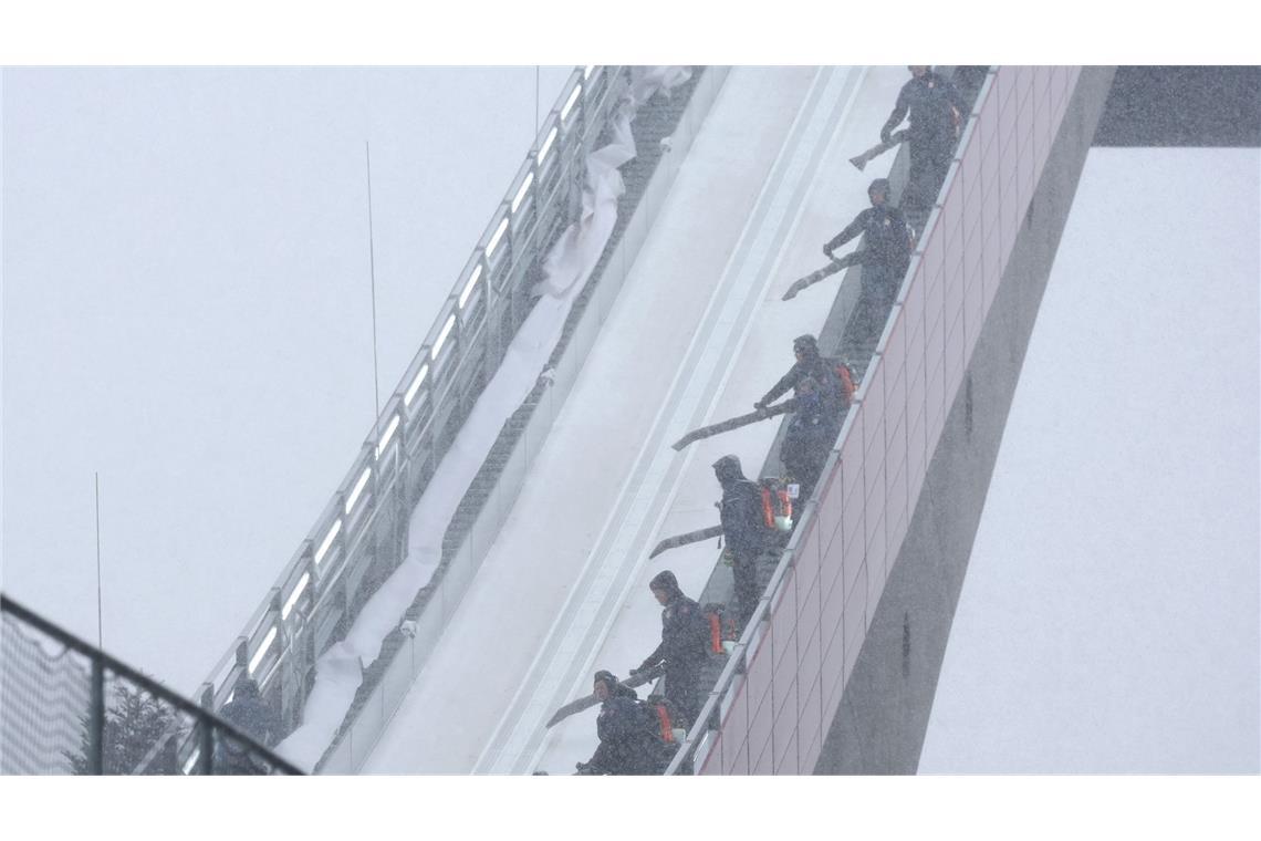 Zu viel des Guten: Mitarbeiter blasen beim Probedurchgang zur WM im Teamfliegen in Oberstdorf Schnee von der Flugschanze.