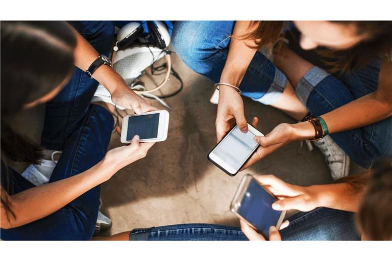 Zu viel online? Eine Gruppe junger Mädchen schaut aufs Handy.
