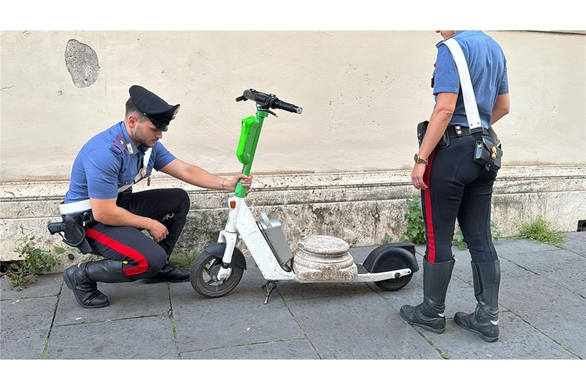 Deutscher fährt antiken Säulensockel auf E-Roller durch Rom Zwei Carabinieri begutachten den Marmorsockel auf einem elektrischen Leihroller.