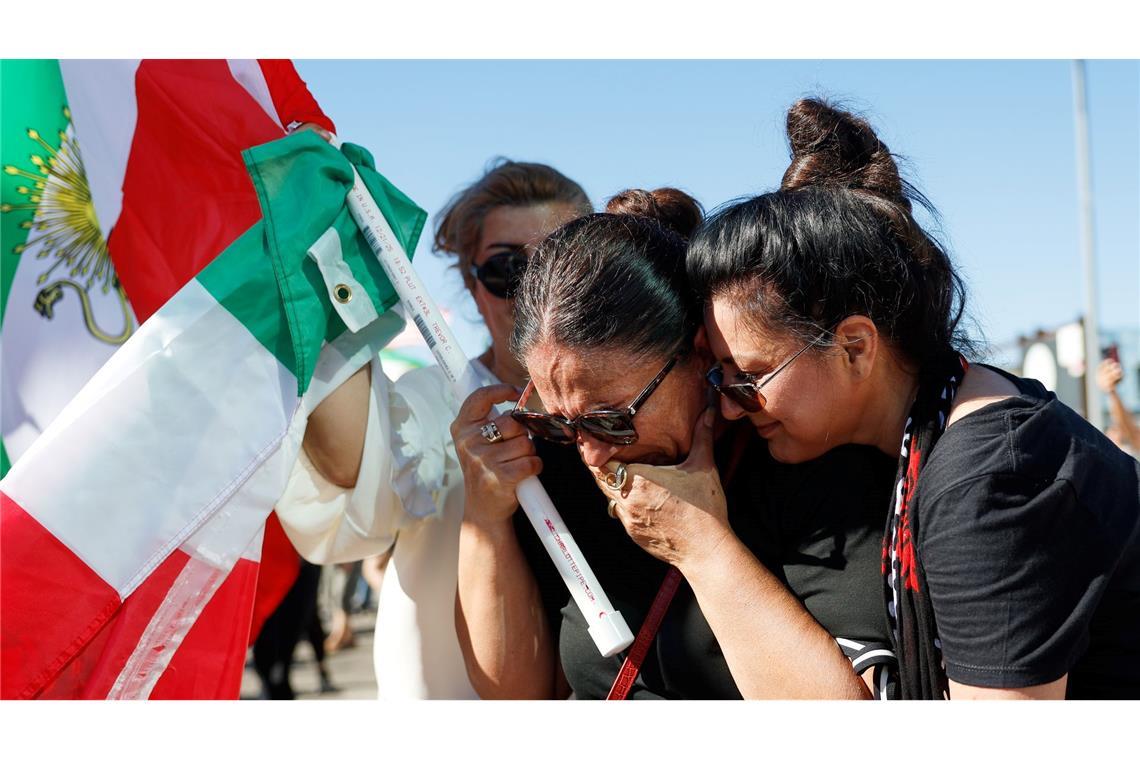 Zwei Frauen umarmen sich während einer Demonstration.