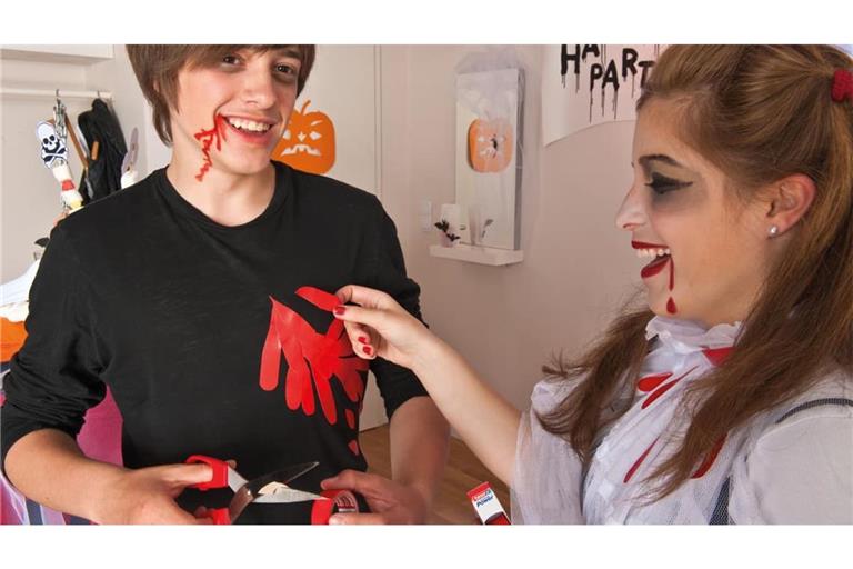 Zwei Kinder verkleiden sich für Halloween: Rotes Gewebeband imitiert Blut: Ausgeschnittene Tropfen und Streifen lassen sich auf ein ausgedientes schwarzes Shirt kleben.