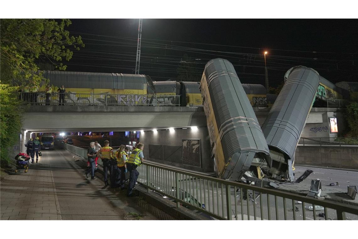 Zwei Waggons eines Güterzugs liegen auf einer Straße in München, nachdem sie von einer Brücke gestürzt sind.